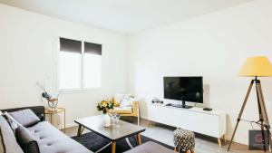 a living room with a couch and a tv at Sanguinet - Élégante maison pour 6 personnes PMR in Sanguinet
