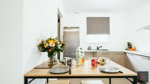 a kitchen with a wooden table with a vase of flowers at Sanguinet - Élégante maison pour 6 personnes PMR in Sanguinet +19 photos