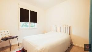 a white bedroom with a bed and a window at Sanguinet - Élégante maison pour 6 personnes PMR in Sanguinet