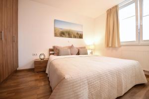 a white bedroom with a large bed and a window at Seedüne 1 in Großenbrode +15 photos