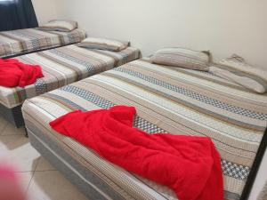 three beds in a room with red sheets at Casa Neia Castro com Piscina e garagem perto da Basilica in Aparecida +18 photos