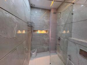 Un baño con ducha con puerta de cristal. en Shri Radha Krishnam, en Barsāna