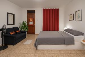 a bedroom with a bed and a couch and a red curtain at RoomsMagisPalmera in Cahuita