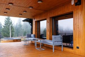 eine Veranda mit zwei Stühlen und einer Bank auf einer Terrasse in der Unterkunft Blackwood Retreat in Neagra Şarului