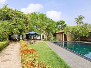 Un jardín con piscina y una casa. en Blue Villa Wadduwa, en Wadduwa