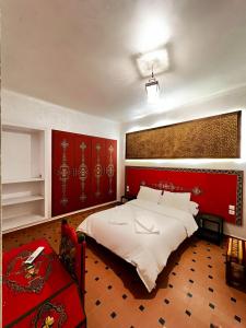 a bedroom with a large bed with a red headboard at Hôtel LAKASBAH Ait Ben Haddou in Aït Benhaddou