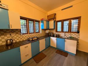 eine große Küche mit blau-weißen Schränken und Fenstern in der Unterkunft Ethnic Family Spot Wayanad in Kenichira