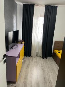 una stanza con una scrivania con una televisione e una finestra di Alex Apartment a Balş