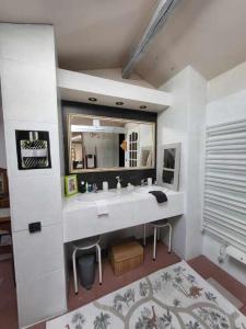 a white bathroom with a sink and a mirror at Les Hirondelles in Saint-Georges-sur-Layon