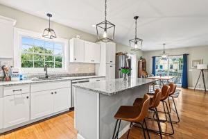 una cocina con armarios blancos y una gran isla con taburetes. en Designer home sleeps 10 winter water views, en South Portland