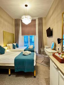 a hotel room with two beds and a chandelier at Queens Park Premier London Hyde Park in London