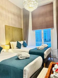 a hotel room with two beds and a chandelier at Queens Park Premier London Hyde Park in London