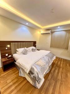 a bedroom with a large bed and a wooden floor at شقق العرين للشقق المخدومة in Jeddah