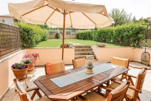 a patio with a wooden table and an umbrella at Nerida House Salonikiou Beach in Akti Salonikiou