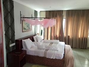 布科巴WalkGard WestLand HOTEl的卧室里有一张床，床单和枕头都是白色的