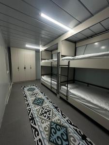 Habitación con 3 literas y alfombra. en Nomad Kyrgyz Hostel, en Bishkek