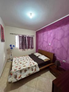 a bedroom with a bed and a purple wall at Tropical Breeze Holidays in Santa Maria