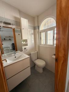 een badkamer met een wastafel en een toilet en een raam bij Casa Familiar Atarfe in Atarfe +15 foto's