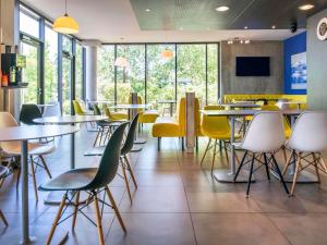 a dining room with tables and yellow chairs at Ibis Budget Archamps Porte de Genève in Archamps