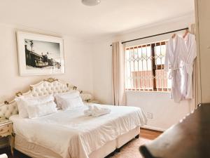 a white bedroom with a bed and a window at Princess Holiday Home in Cape Town