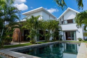 a villa with a swimming pool in front of a house at Summer Palms Villa in Flic-en-Flac