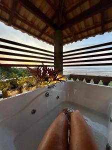a person sitting in a bath tub with their feet at Casa Maria Areia Boutique in Camocim