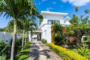 a white house with palm trees and a pathway at Summer Palms Villa in Flic-en-Flac