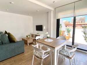 un soggiorno con tavolo, sedie e divano di Novamar Apartamentos a Fuengirola