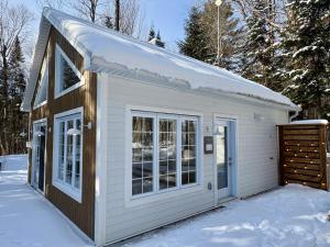 un petit hangar blanc avec une porte dans la neige dans l'établissement Pur Nature Garthby et Sauna, à Saint-Gérard