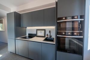a kitchen with gray cabinets and a stove top oven at Uliveto Moriondo in Salò