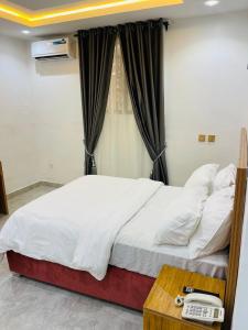 a bedroom with a bed with a phone on a table at Nucfam Hotel Ojodu in Eggan +5 photos