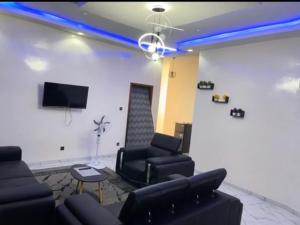 a living room with a couch and chairs and a tv at Superetoile in Rufisque