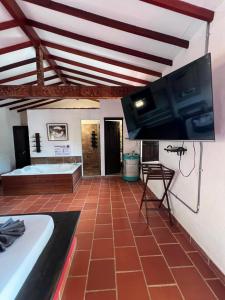 sala de estar con TV y suelo de baldosa. en Hotel La Choza, en El Peñol