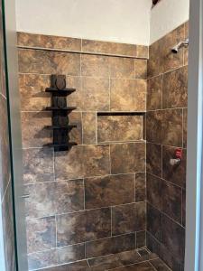 y baño con ducha y pared de azulejos. en Hotel La Choza, en El Peñol