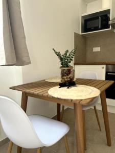 ein Holztisch mit zwei weißen Stühlen und einer Pflanze darauf in der Unterkunft Appart Cosy près de la Gare & Centre ville in Saint-Étienne