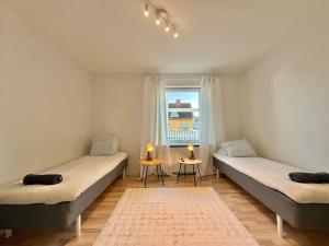 two beds in a room with a window at Workers Big Villa - 5 BR - 2 Bath - 10 min to Volvo in Gothenburg
