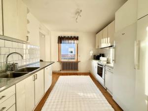 a kitchen with white cabinets and a sink and a window at Workers Big Villa - 5 BR - 2 Bath - 10 min to Volvo in Gothenburg