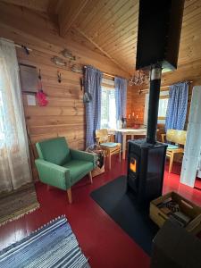 a living room with a fireplace and a green chair at Forestry cabin and sauna cabin in Halmevaara +12 photos