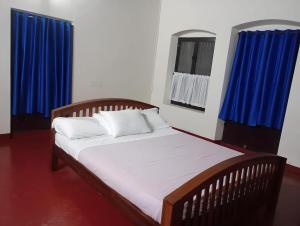 阿勒皮Anna's Heritage bungalow的蓝色窗帘的房间的一张床位