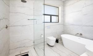 a bathroom with a tub and a glass shower at Escape to Paradise in Mossel Bay +22 photos