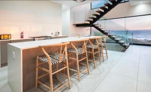 a kitchen with a bar with stools and a staircase at Escape to Paradise in Mossel Bay