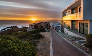 a house on the beach with the sunset in the background at Escape to Paradise in Mossel Bay