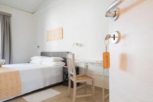 Un dormitorio con una cama y un escritorio con una silla. en I Centenari Longevity Rooms, en Lotzorai