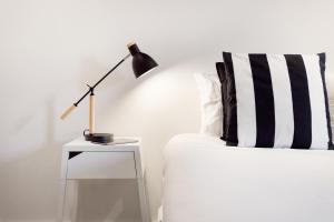 a bed with a lamp on a night stand next to a table with a black at Aveiro Urban Apartment by Visit-Aveiro in Aveiro