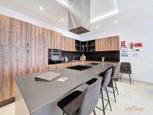 a kitchen with a large island with bar chairs at Malta Rooftop Villa with Private Plunge Pool & BBQ in Hal Ghaxiak