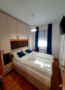 a bedroom with a large white bed with blue pillows at Apartman Felicita 2 Zlatibor in Zlatibor