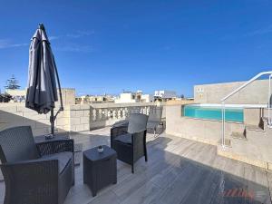 a patio with an umbrella and chairs and a pool at Malta Rooftop Villa with Private Plunge Pool & BBQ in Hal Ghaxiak