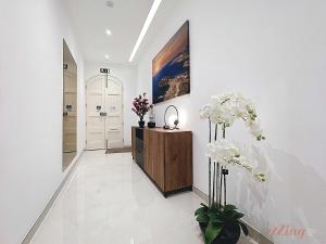 a hallway with white walls and white floors and flowers at Malta Rooftop Villa with Private Plunge Pool & BBQ in Hal Ghaxiak +26 photos