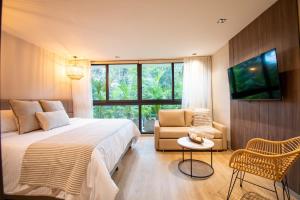 a bedroom with a bed and a tv and a chair at Hotel Salento Real Eje Cafetero in Salento