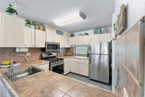 una cucina con mobili bianchi e un frigorifero in acciaio inossidabile di Kihei Akahi B102 a Wailea Altre 17 foto